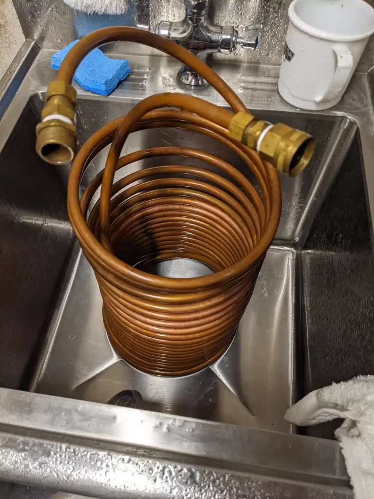 dirty immersion chiller in a sink getting ready to be cleaned.