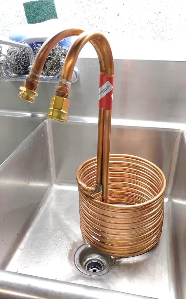 immersion chiller in a stainless steel sink preparing to be cleaned.